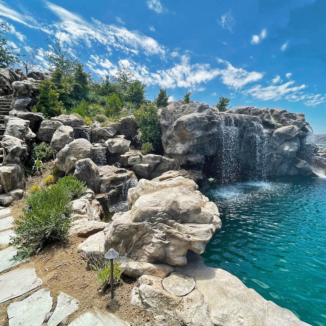 Finished Simi Valley grotto with cascading waterfalls into a deep-blue pool, stone steps and lush planting